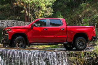 Pickup roja con GM Garantía Plus en zona boscosa